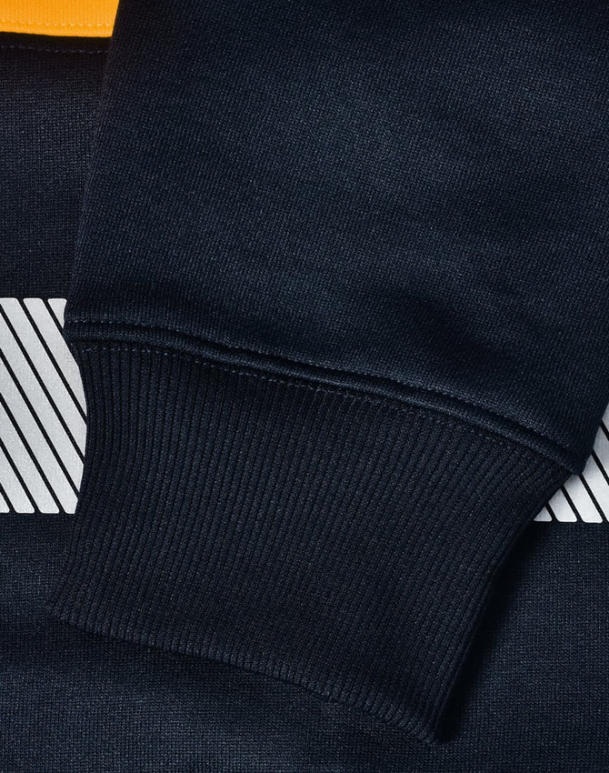 A close-up of a navy blue jumper with a striped design and ribbed cuffs, featuring a logo.