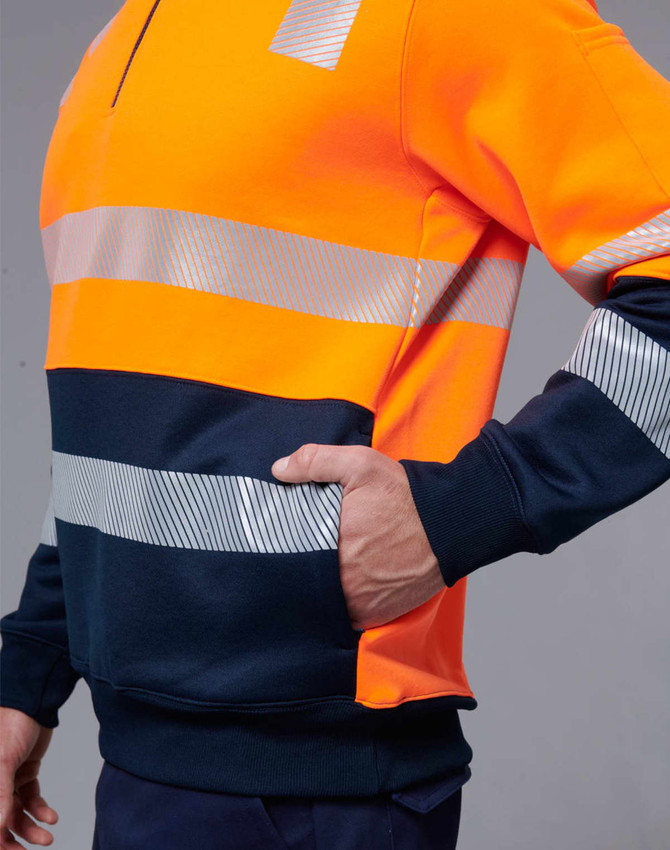 A high-visibility jumper featuring bright orange and navy blue with reflective stripes. It includes a side pocket and has a logo.