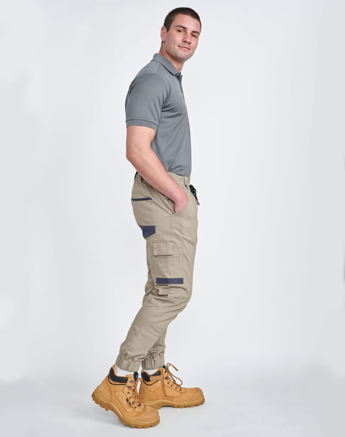 Unisex cotton stretch drill cuffed work pants in khaki with side pockets, paired with a grey polo and yellow work boots.