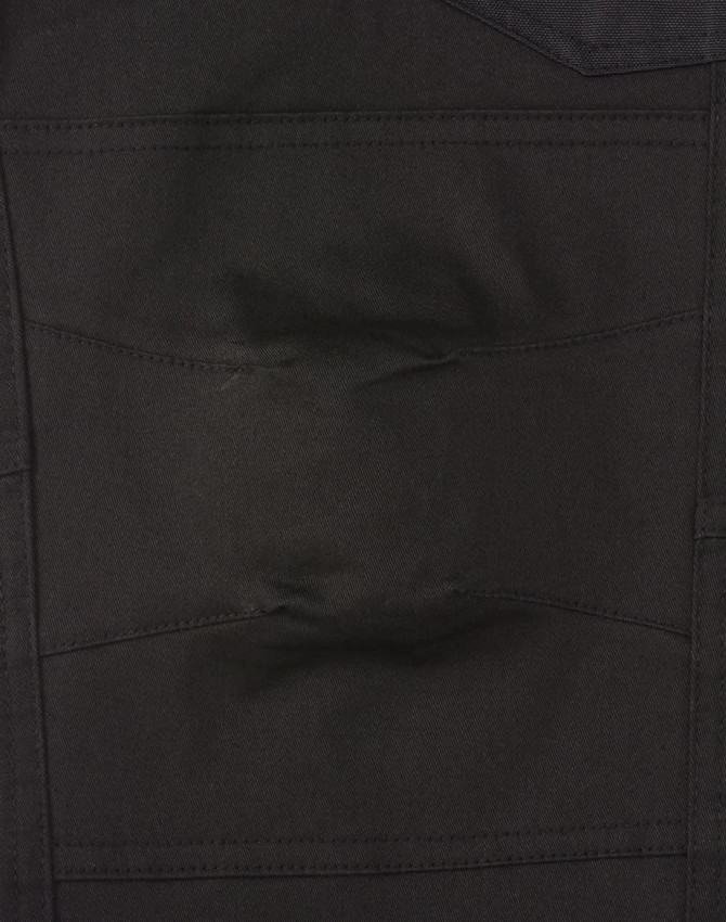 A close-up view of unisex black cotton stretch drill cuffed work pants, featuring pockets and a sturdy design.