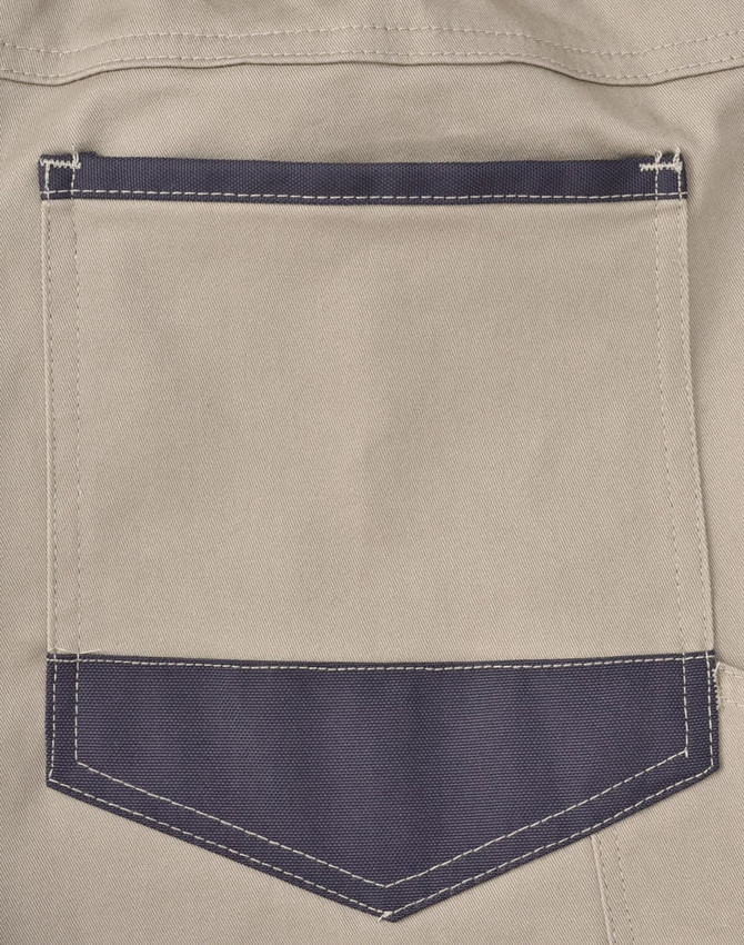 A close-up of a beige work pant's back pocket with a dark navy patch and visible stitching details.