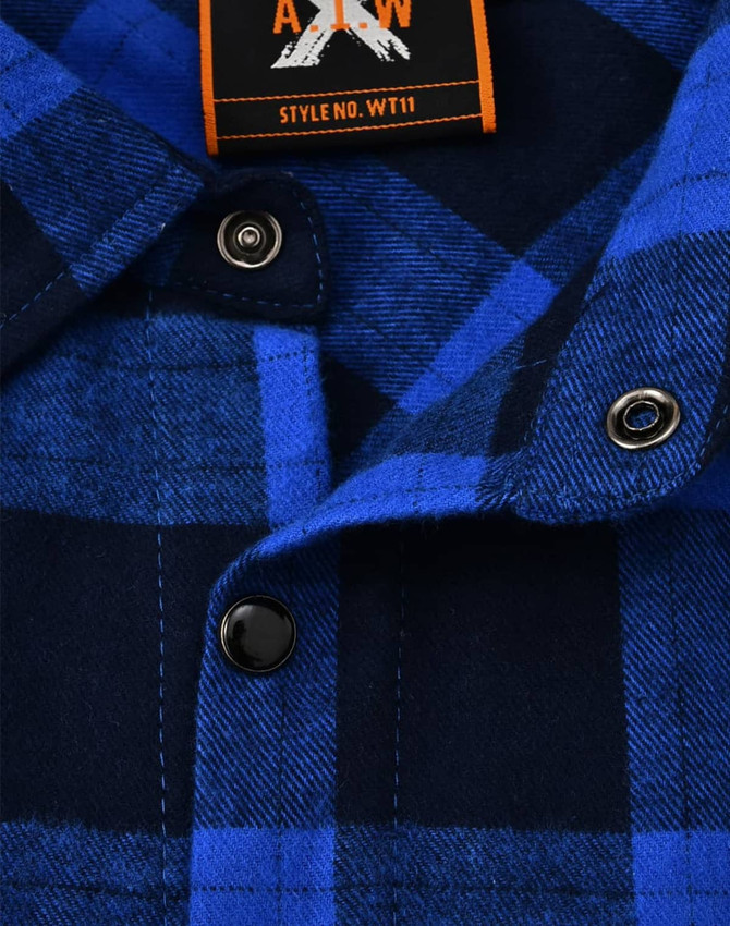 A close-up of a navy and blue flannel plaid button-up shirt featuring black buttons and a brand label.