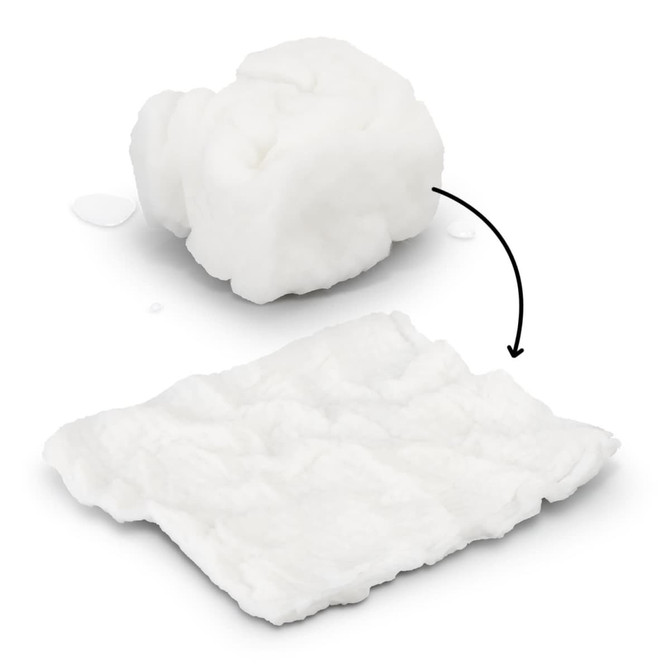 A compressed white towel, transforming from a small compact shape to a flat, textured cloth, with water droplets nearby.