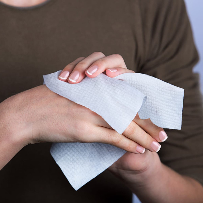 A hand holding a small, white compressed towel, showcasing its texture and design.