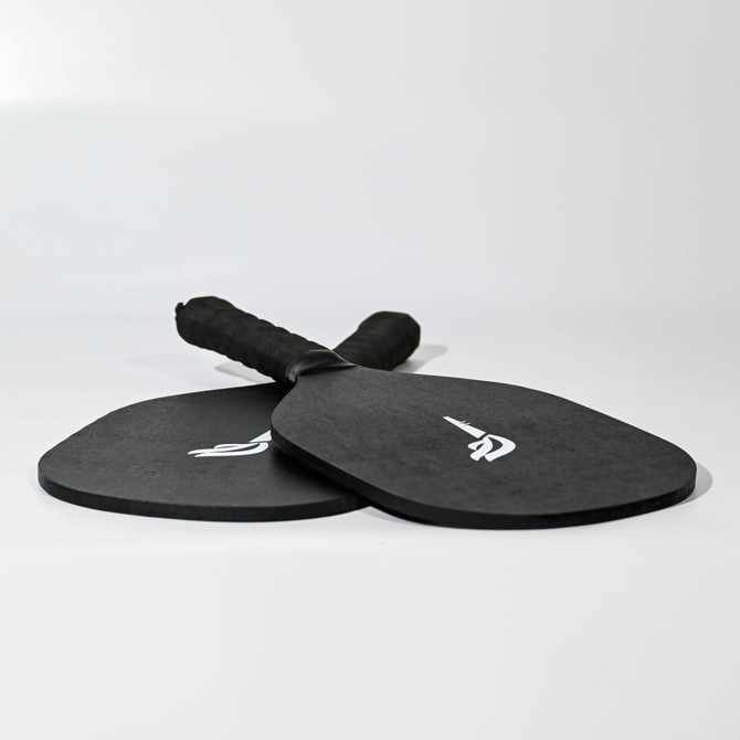 A black pickleball set featuring two paddles with grip handles, each adorned with a logo.