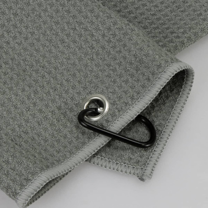 A grey waffle golf towel featuring a silver grommet and a black carabiner for attachment.
