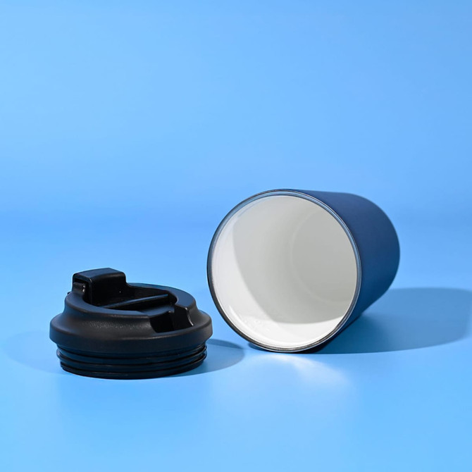 A travel cup in dark blue with a black lid, featuring a logo, set against a light blue background.
