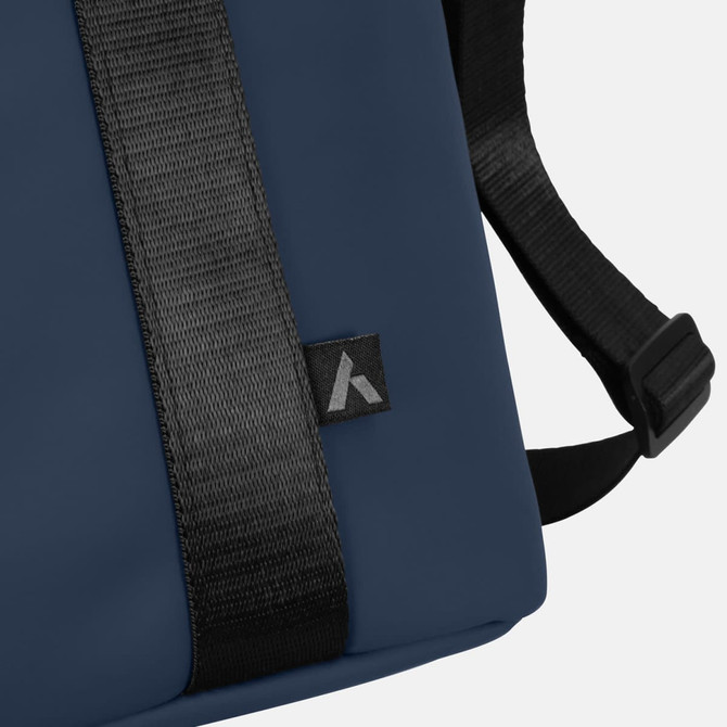 A soft-touch cooler bag in navy blue with a black strap and a small logo on the side.