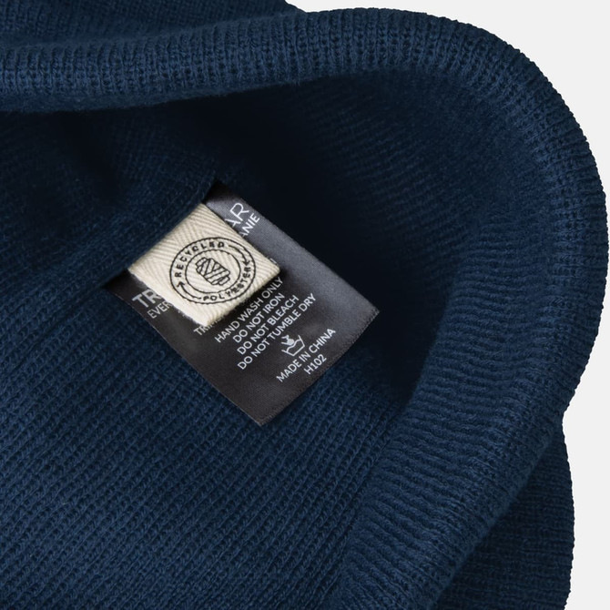 A navy blue beanie with a textured exterior and a label inside. The beanie features a visible logo.
