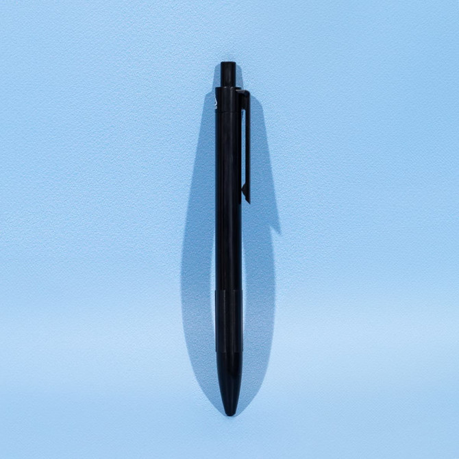 A black eco plastic ball pen lies flat against a light blue background. It features a clip and a rounded tip.