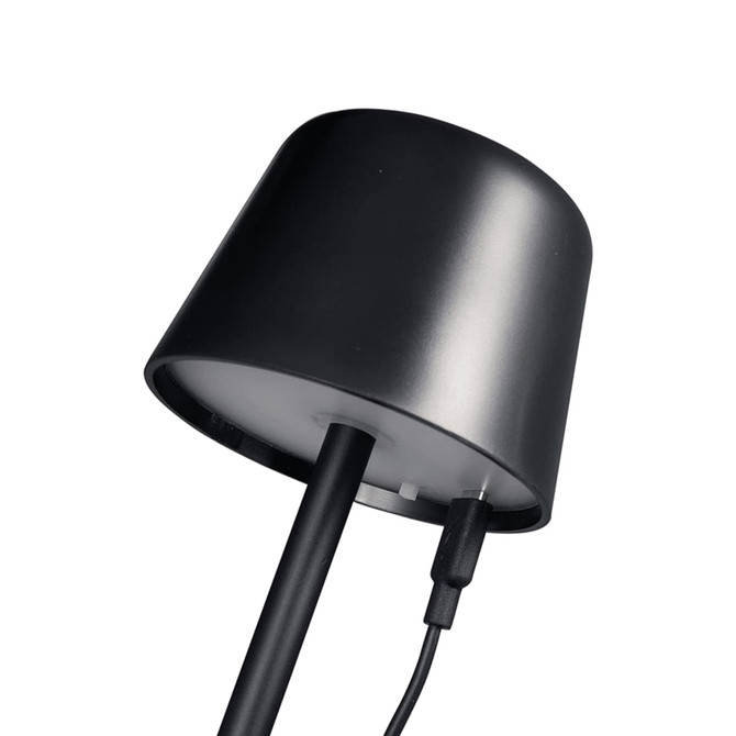 A black mini rechargeable lamp with a curved top and charging cable attached. It features a clean, modern design.