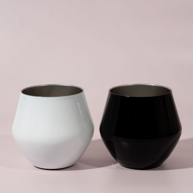Two detachable wine glasses, one white and one black, displayed against a soft pink background.
