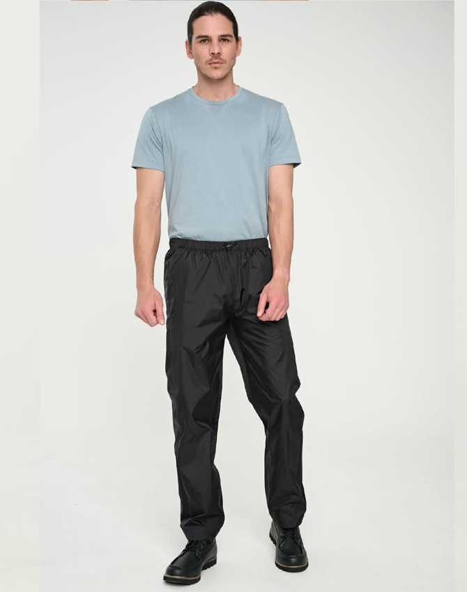 Lightweight black nylon waterproof rain pants displayed on a male model wearing a blue t-shirt. Features an elastic waistband.