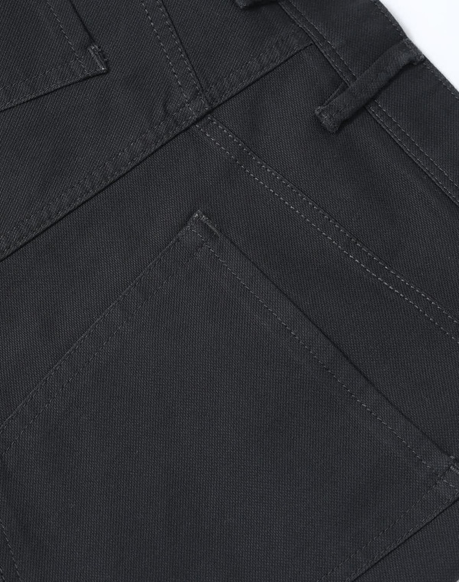 A close-up of dark grey flexi chino pants featuring detailed stitching and a back pocket design.