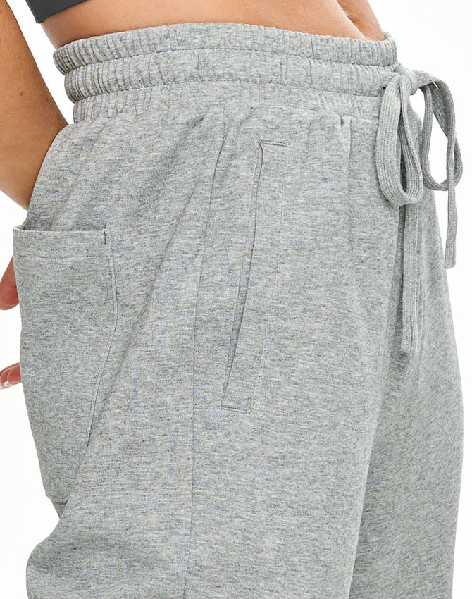 A pair of grey unisex sweatpants with side pockets and an elastic waistband. Features a brand logo.