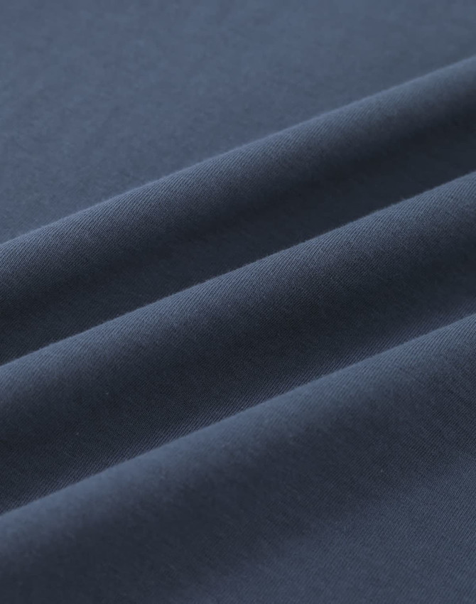 A close-up of soft, dark navy cotton fabric with smooth folds, showing its texture and quality.