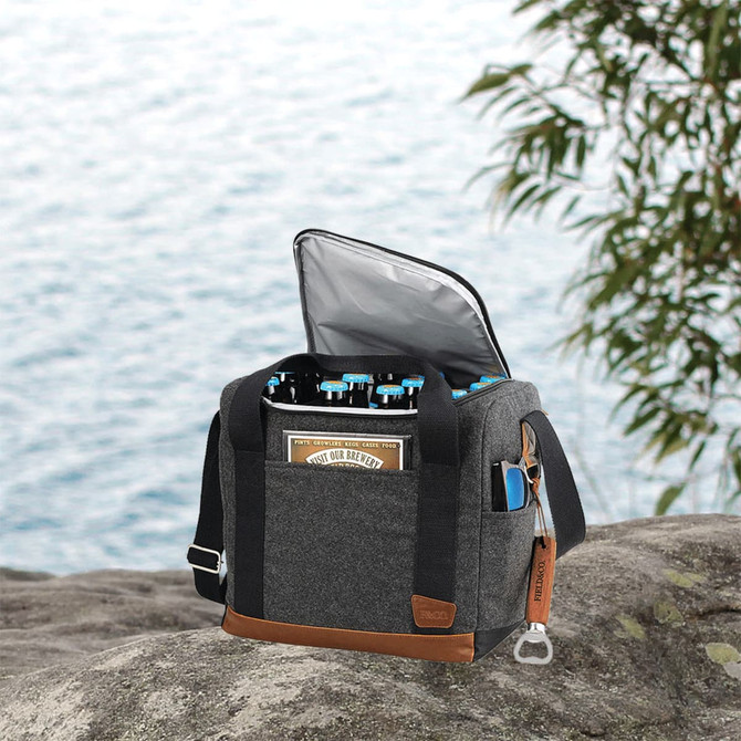A grey cooler bag with a brown base, filled with bottles, set against a scenic outdoor background.