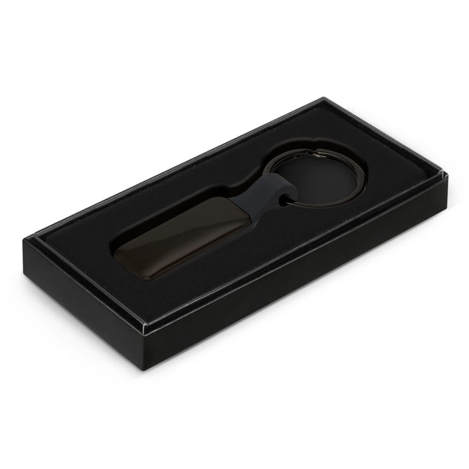 A rectangular black key ring presented in a black box with an insert. The key ring includes a logo.