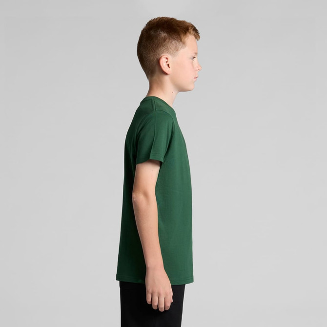 A green youth staple tee displayed on a child, showcasing a side view of the shirt's fit and design.