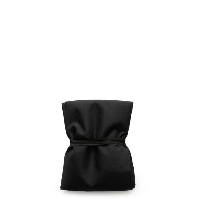 A reusable grocery bag in black, compactly folded with an elastic band securing it.