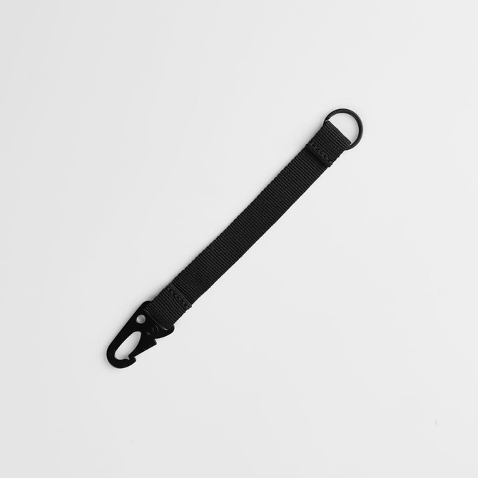 A black keychain with a clip and a circular ring, made of durable material.