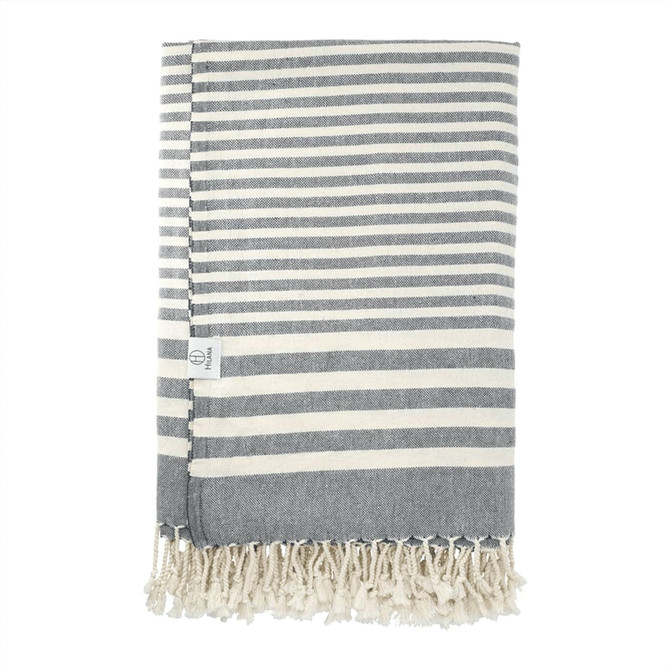 A striped throw blanket in grey and cream, featuring a fringed edge and a small logo.