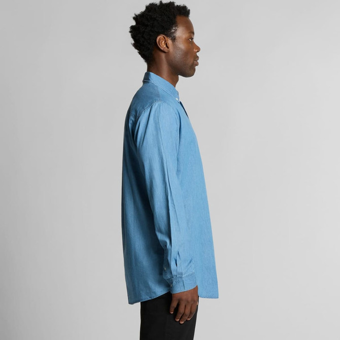 A blue denim button-up shirt displayed on a model from the side, featuring long sleeves and a collar.