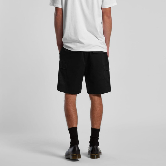 Black cargo walk shorts with side pockets, worn by a person facing away, paired with a white t-shirt and black shoes.