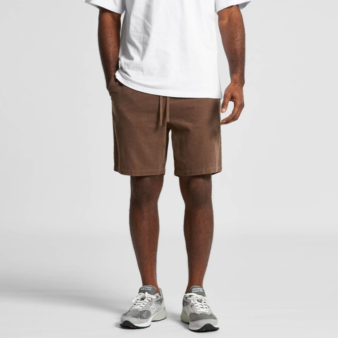 Brown dress shorts with side pockets and a drawstring waist, worn with a plain white shirt and grey sneakers.