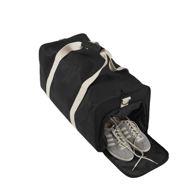 A black duffle bag with a zipper, featuring a pair of grey and white sneakers peeking out from the side compartment.