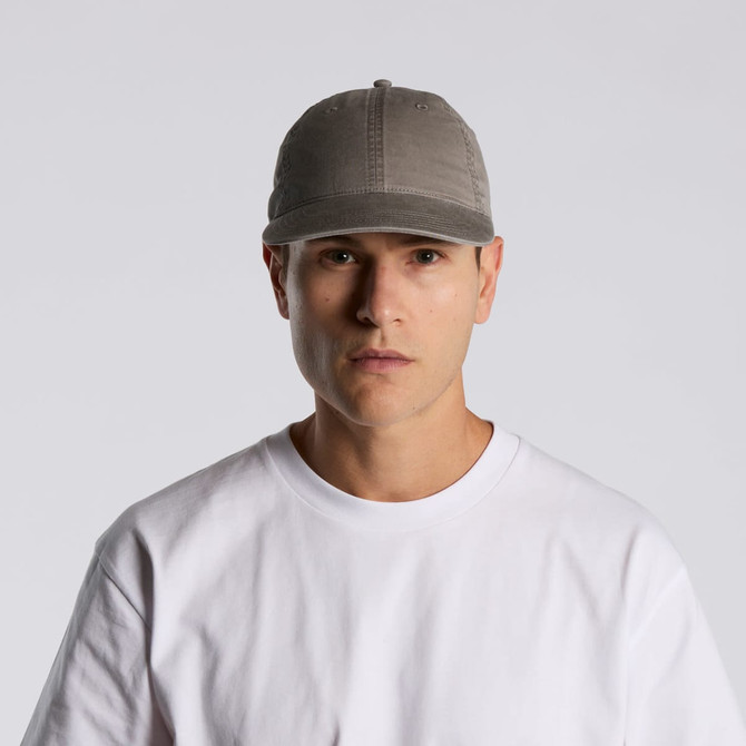 A grey cap with a rounded peak, featuring a logo and worn by a model in a plain white T-shirt.