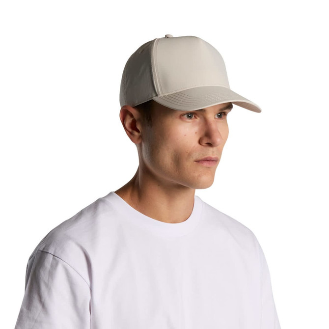 A beige nylon cap on a model, featuring a structured design and a logo.
