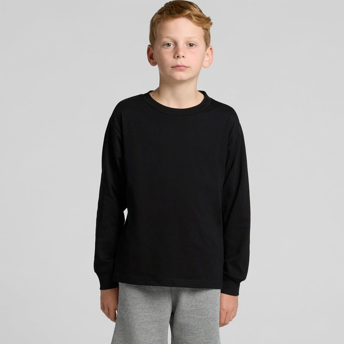 A black long-sleeve t-shirt for youth modelled by a child, paired with grey pants. The shirt features a logo.