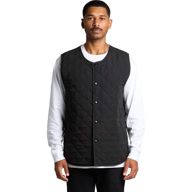 A black quilted vest with snap buttons, worn over a white long-sleeve top. The vest has a quilted texture and a minimal design.