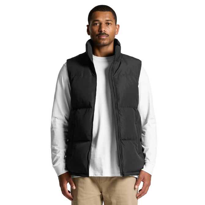 A puffer vest in black, featuring a zip closure and a high collar, worn over a white long-sleeve shirt.
