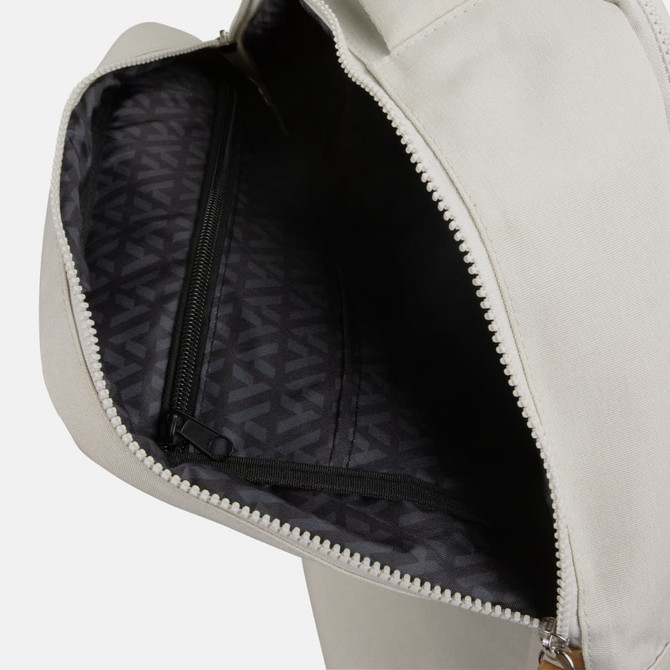 An open grey backpack featuring a dark patterned interior and a zippered pocket.