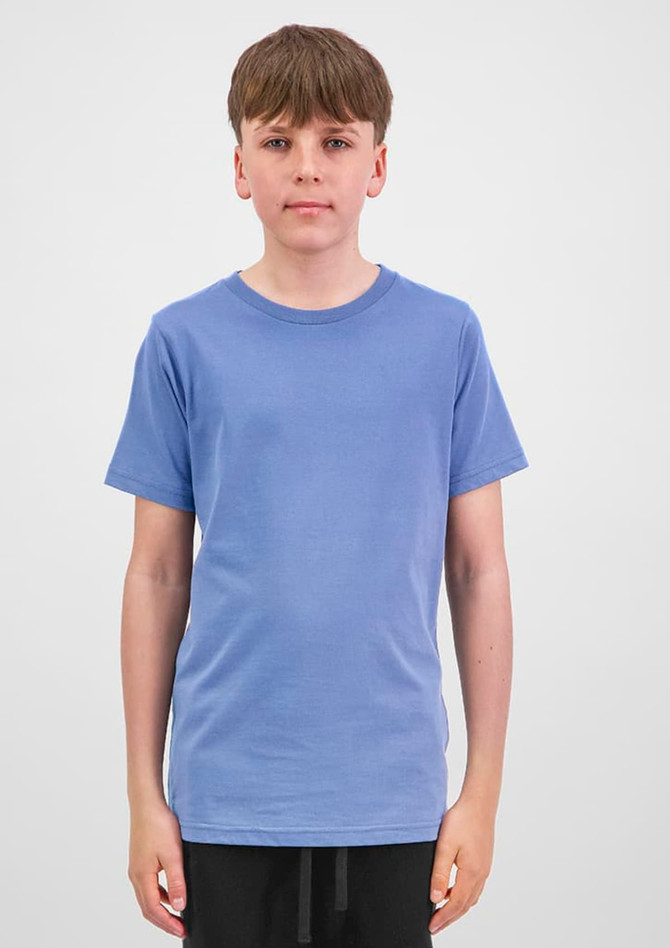 A young person wearing a short sleeve tee in light blue, standing against a plain background. The tee has a brand logo.