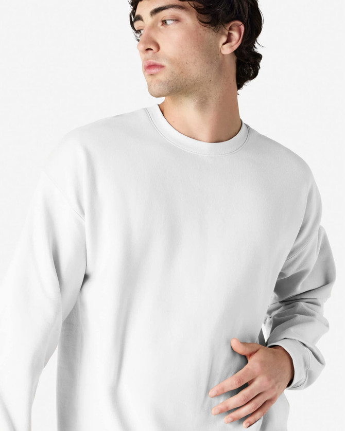 A white Gildan Softstyle adult sweatshirt is worn by a model with dark hair, featuring a relaxed fit and long sleeves.