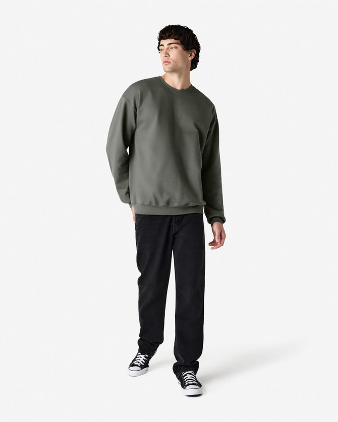 A green Gildan Softstyle adult sweatshirt displayed on a model, paired with black pants and sneakers.