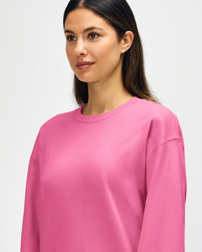 A pink Gildan Softstyle adult sweatshirt featuring a crew neck and long sleeves, with a logo on the front.