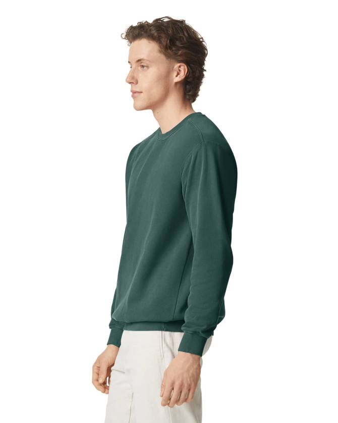 A green adult crewneck sweatshirt is displayed on a model from a side view. It features a simple design and has a logo.