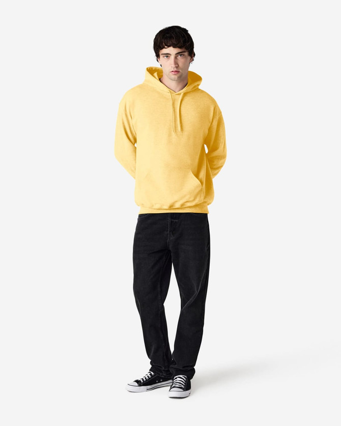 A yellow hooded sweatshirt worn by a model, paired with black jeans and sneakers, featuring a logo.