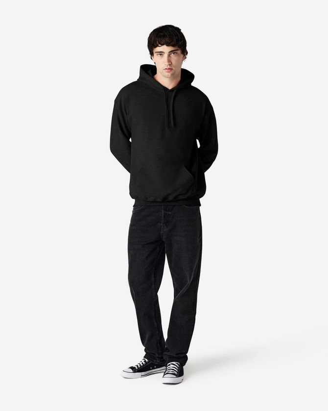 A black Gildan Softstyle adult hooded sweatshirt worn by a model with dark jeans and sneakers, featuring a logo.