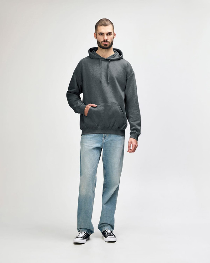 A green Gildan Softstyle adult hooded sweatshirt worn by a model, paired with dark jeans and sneakers.