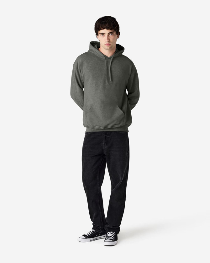 A green Gildan Softstyle adult hooded sweatshirt worn by a model, paired with dark jeans and sneakers.