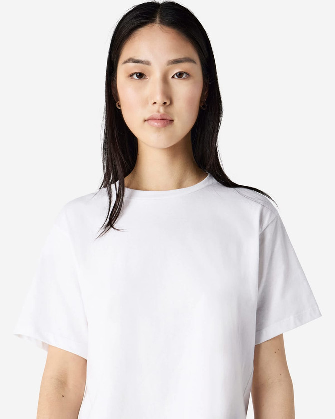 A white women's fine jersey boxy t-shirt displayed on a model, featuring a minimalistic design and an attached logo.