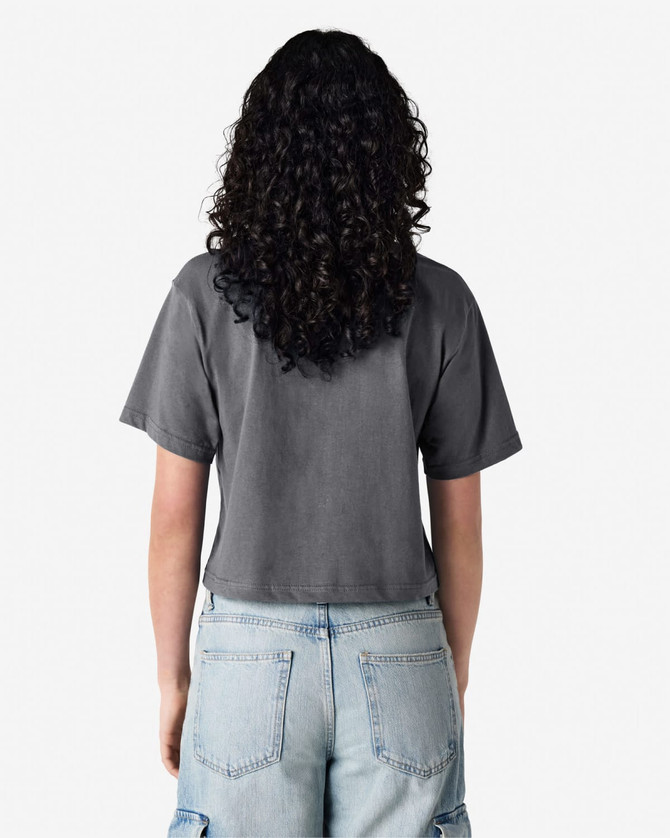 A grey boxy t-shirt is worn by a person with curly hair, standing with their back to the camera.
