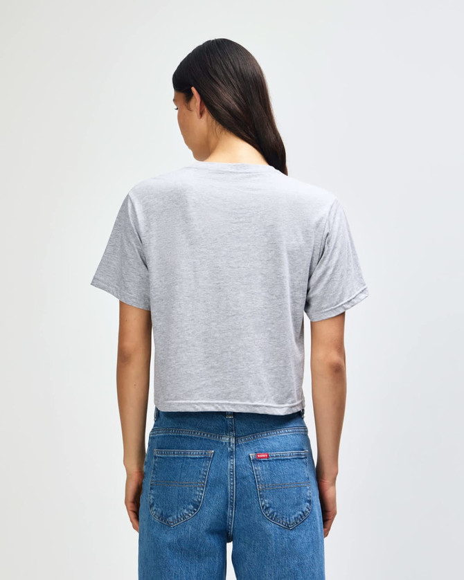 A women’s grey boxy t-shirt with a crew neck, displayed from the back, paired with blue jeans.