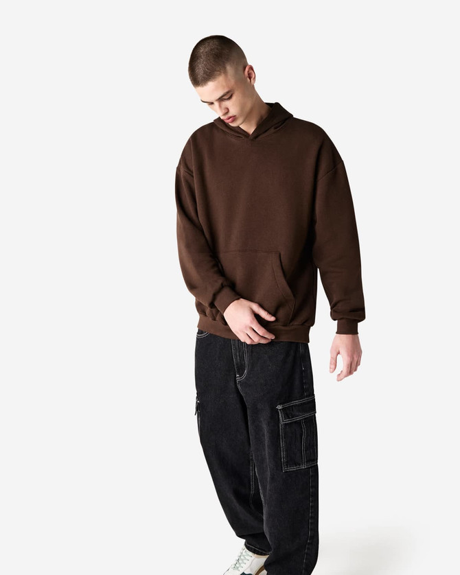 A unisex hooded sweatshirt in brown, featuring a front pocket and paired with black cargo pants.