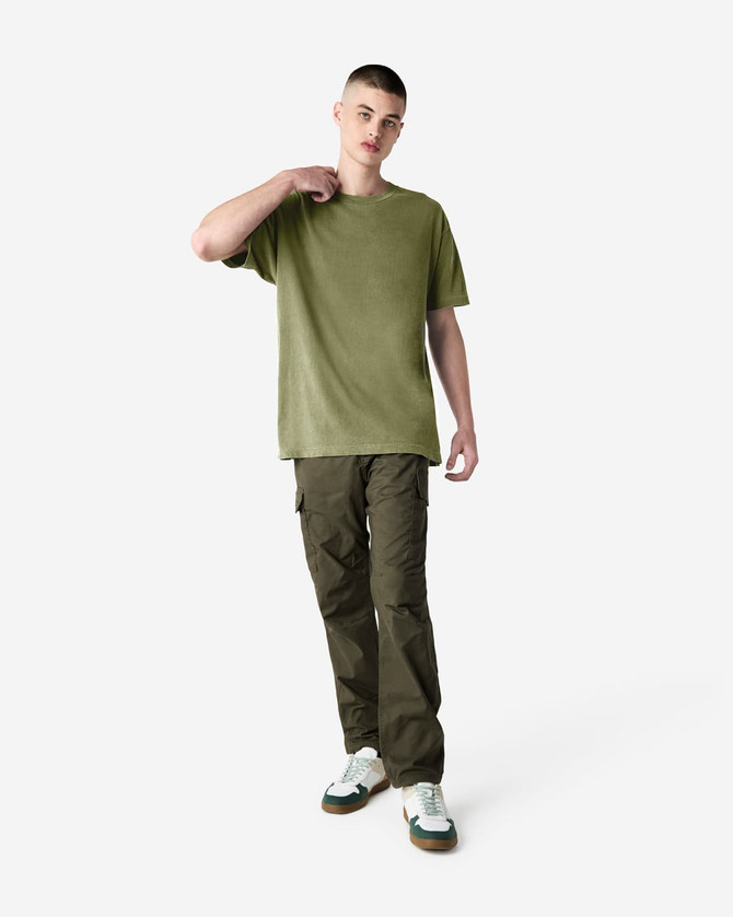 A green heavyweight cotton t-shirt worn by a model, paired with cargo pants and casual shoes, with a subtle logo.